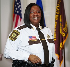 Indoor photo of sheriff with flags in background