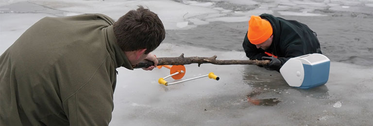 a man giving a branch to a man stuck in the ice