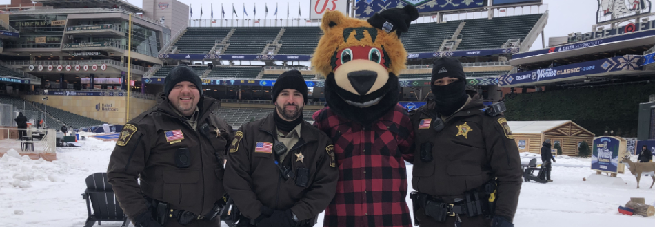 3 uniformed sheriff employees standing with Nordy the Minnesota Wild mascot