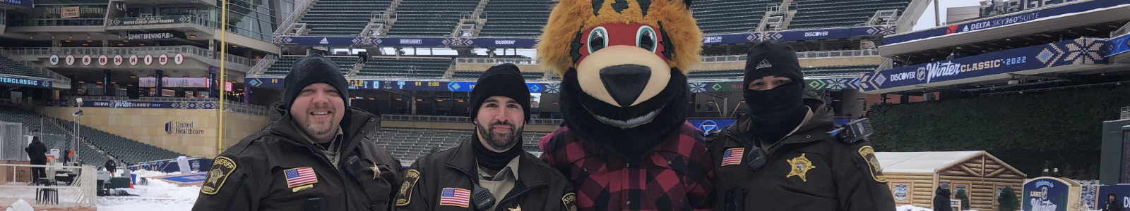 3 uniformed sheriff employees standing with Nordy the Minnesota Wild mascot